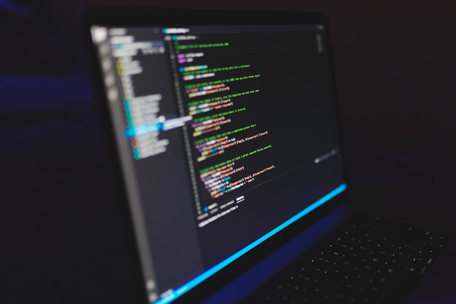 A close-up view of a laptop screen displaying lines of colorful code on a dark background, with the keyboard visible at the bottom. The screen shows a programming interface with multiple lines of text